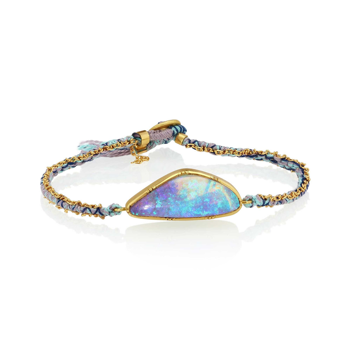 A gold-plated bracelet featuring a large, teardrop-shaped iridescent boulder opal stone with blue, purple, and green flashes, set on a braided blue and gold cord with a small tassel.