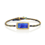 Silk bracelet with blue boulder opal stone and gold chain on a white background