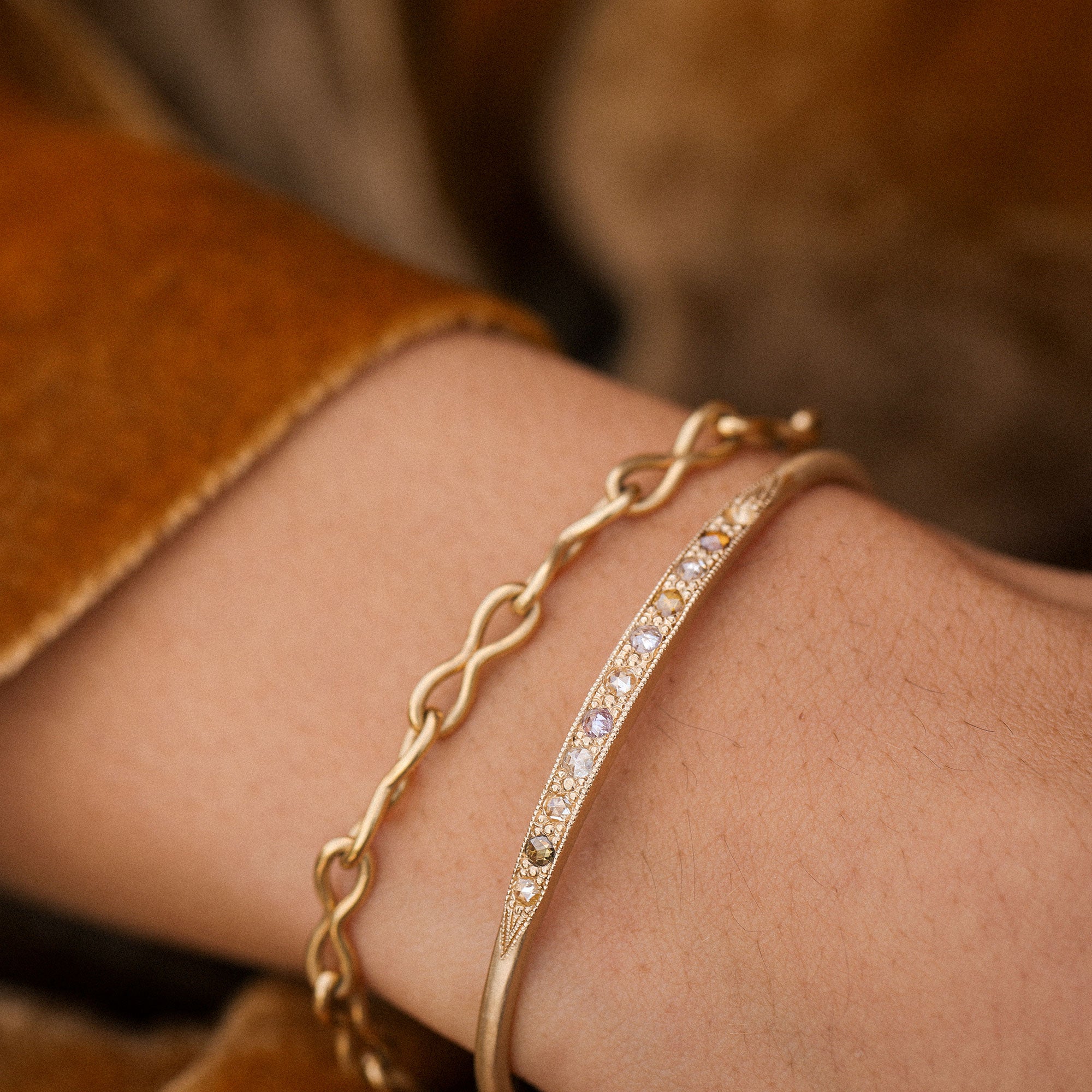 Gold bracelet with chain design on a wrist against a blurred background