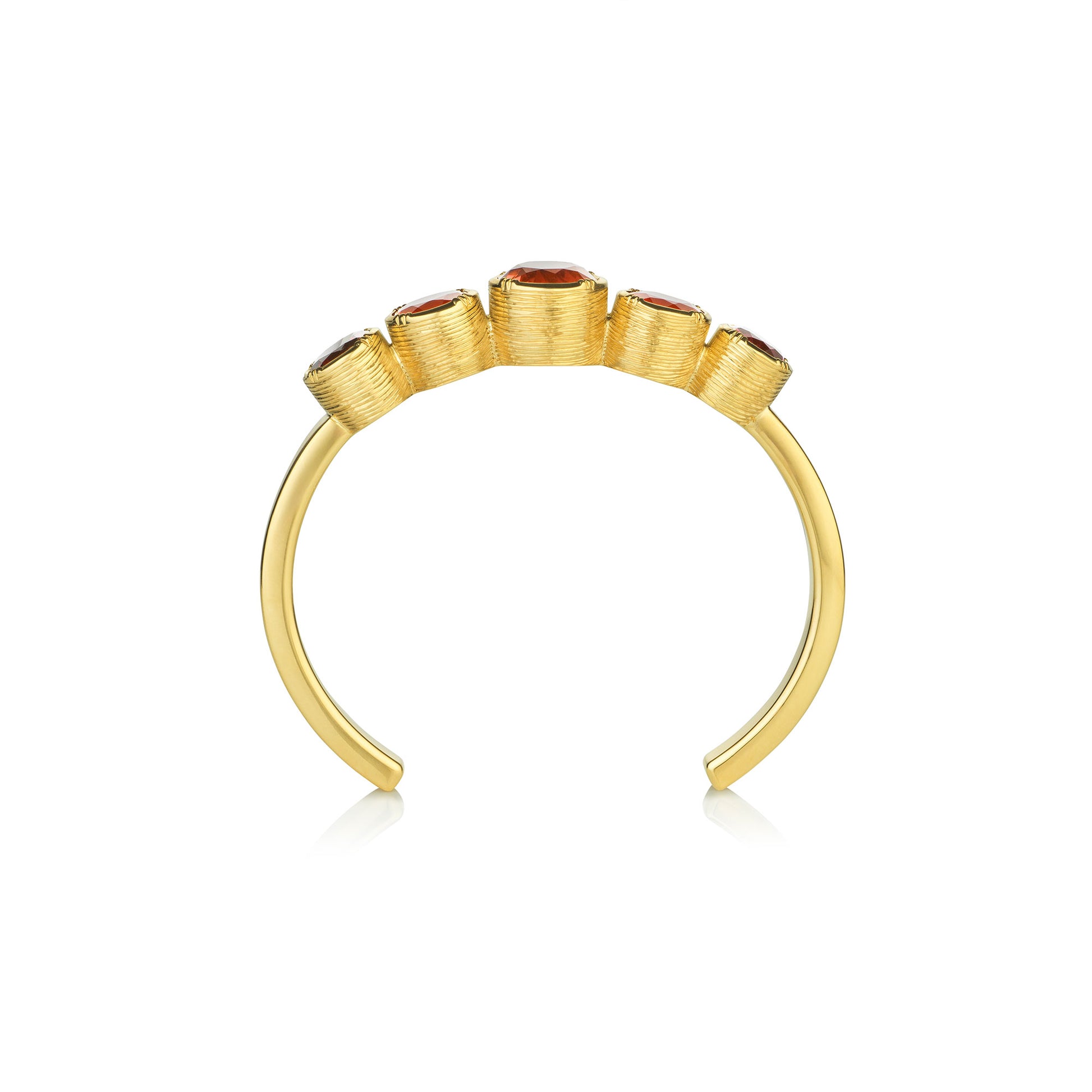 side view of a gold hand engraved cuff with fire opal garnets and tourmalines on a white background.