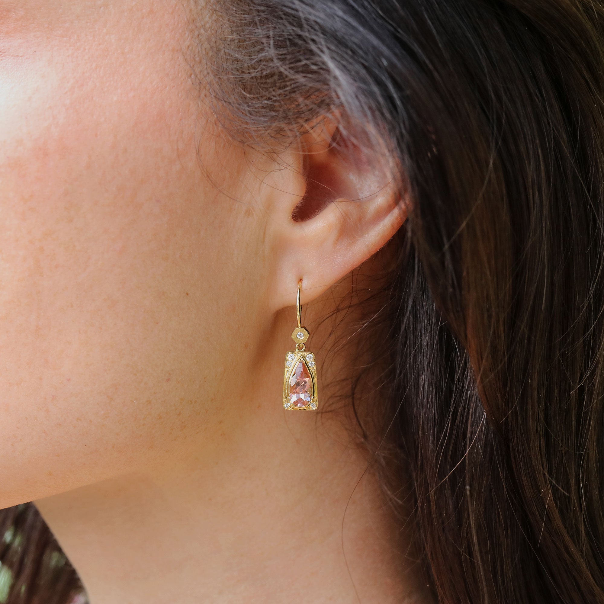 Close up of ear with earring with pear shaped pink tourmaline and diamond accents by Brooke Gregson.