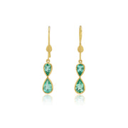 Gold earrings with emerald gemstones in an infinity shape on a white background