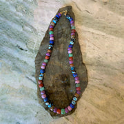 Multicolored beaded necklace on a rough stone surface