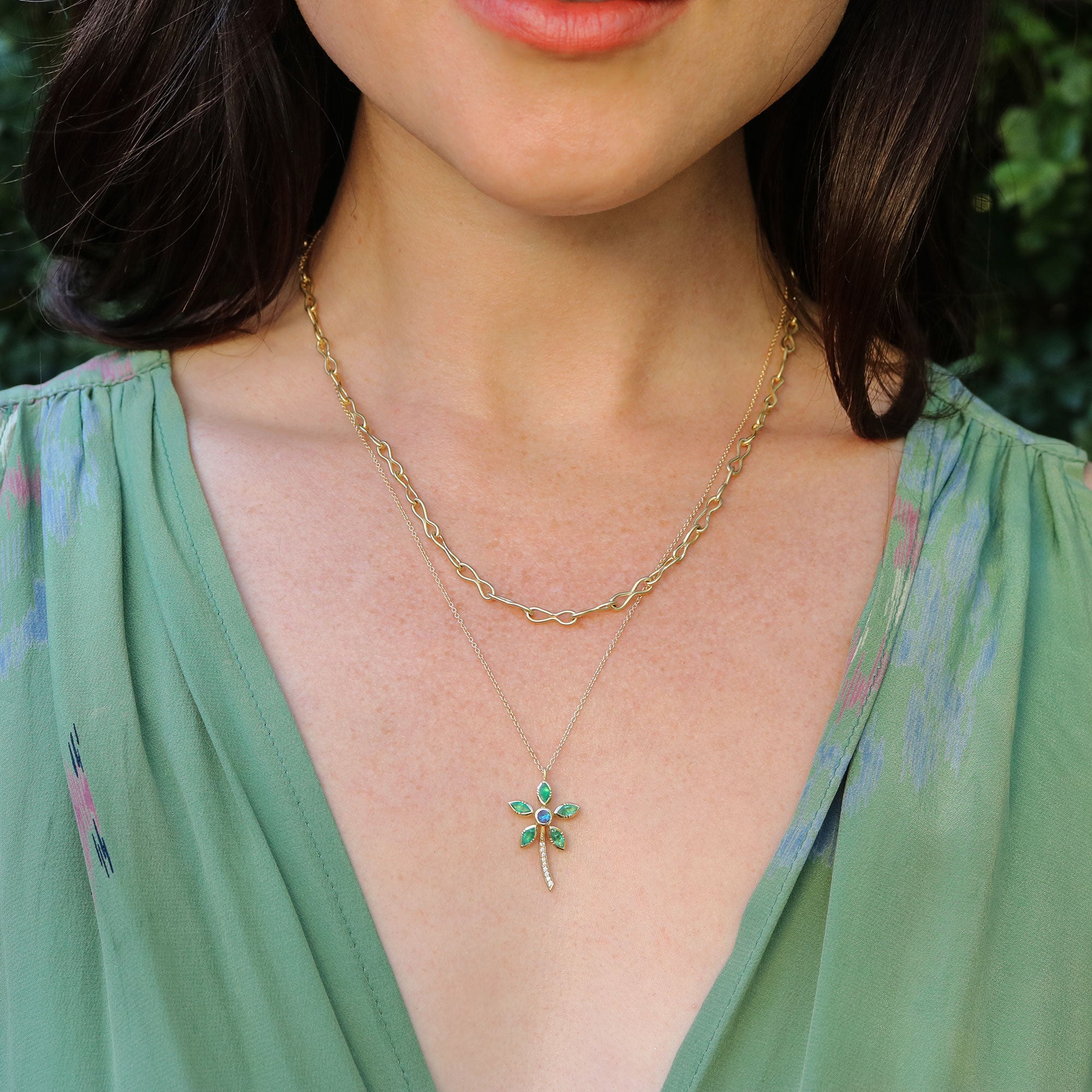 Girl wearing necklace with daisy flower pendant with emeralds, boulder opal, and diamonds.