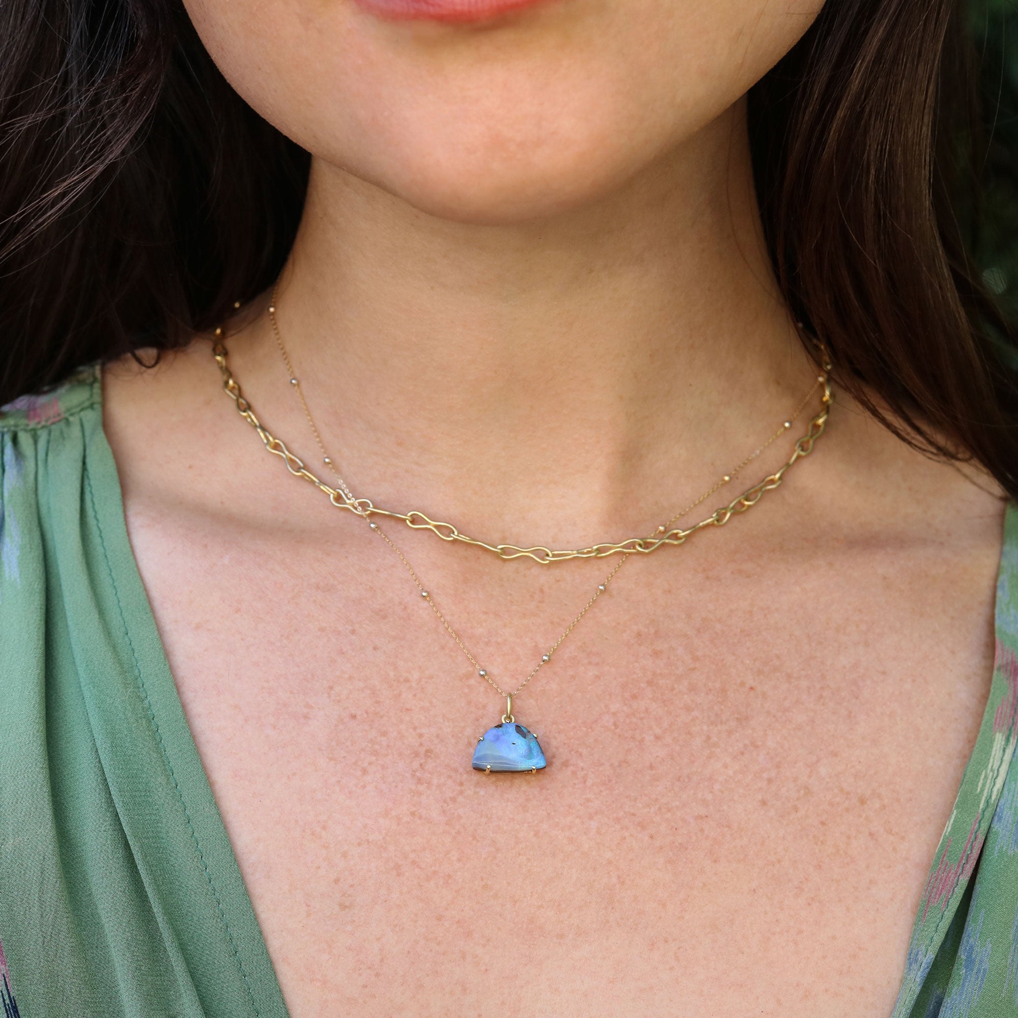 Girl wearing an 18k gold necklace with boulder opal pendant by Brooke Gregson.