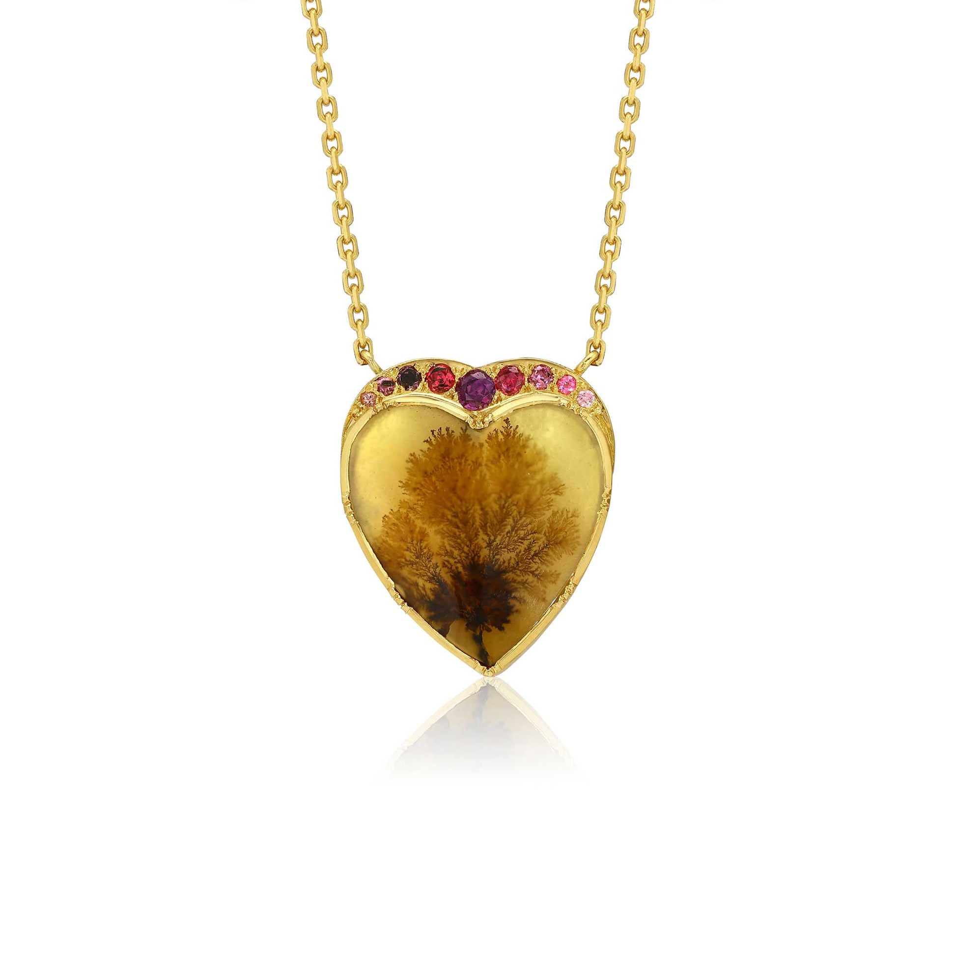 A gold heart-shaped pendant necklace featuring a botanical dendritic agate inside, accented with small pink gemstones along the top curve, shown on a white background with a soft reflection.
