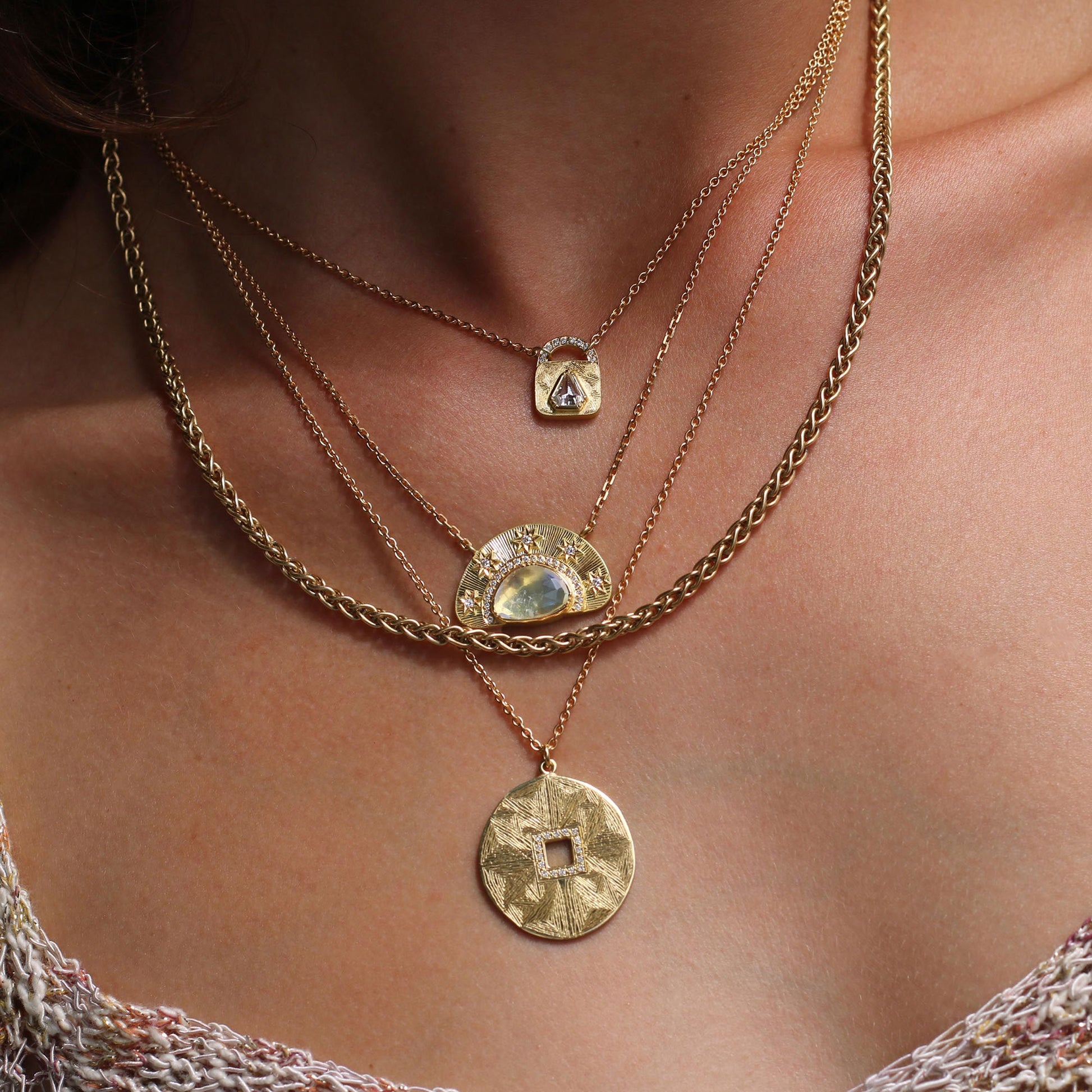 woman wearing a stack of necklaces. One of them is a hera mandala engraved circular pendant necklace.