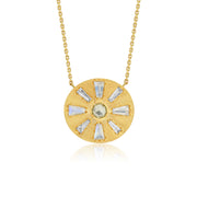 A gold circular pendant necklace featuring a sunburst design with clear baguette-cut diamond stones and a central round pale green diamond gemstone, suspended from a delicate gold chain against a white background.