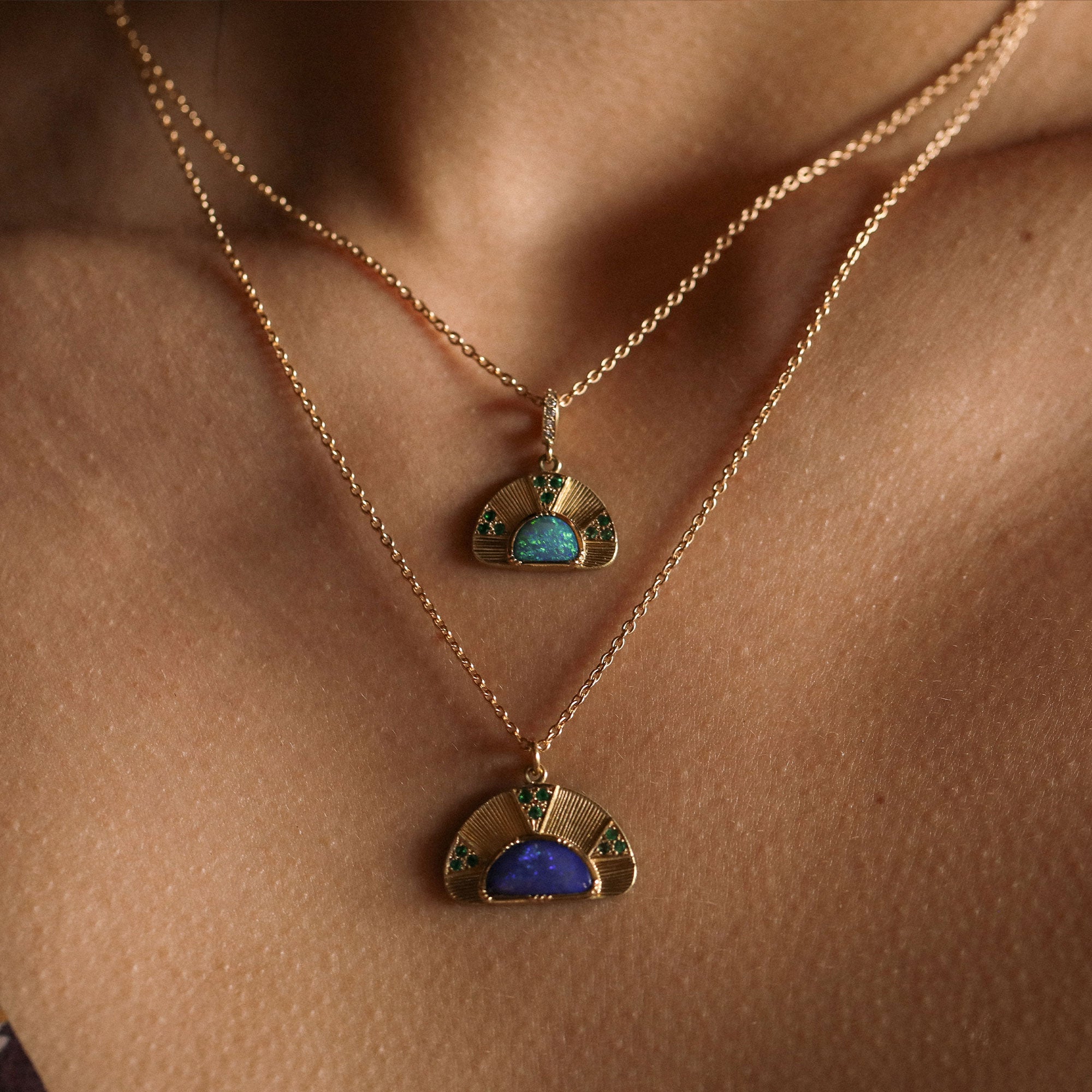 Two gold necklaces with opal gemstone pendants on a person's neck.