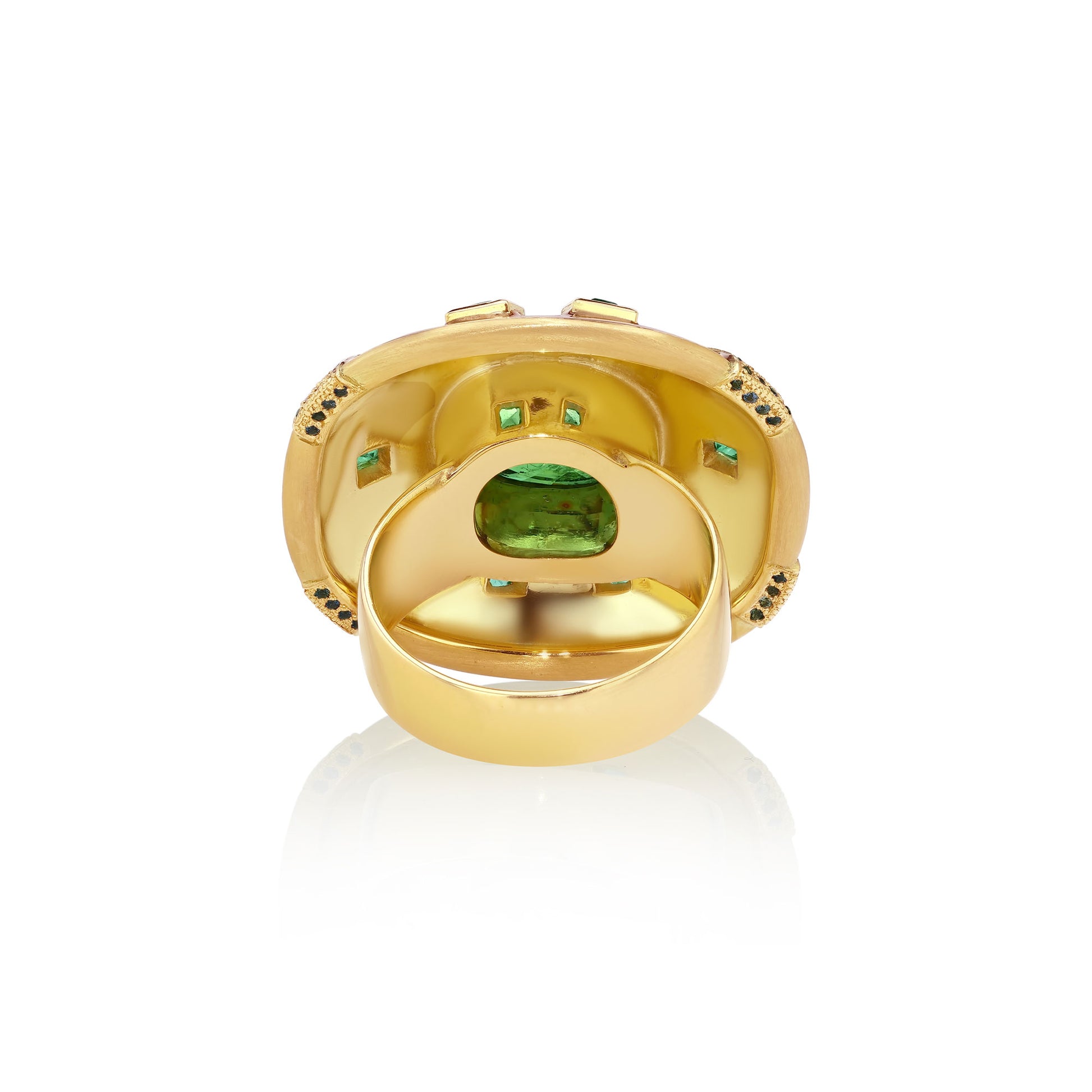Back view of decorative ring with green tsavorites and emeralds and blue sapphires with enameling and engraving on a white background.