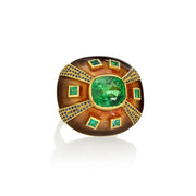 Decorative ring with green tsavorites and emeralds and blue sapphires with enameling and engraving on a white background.