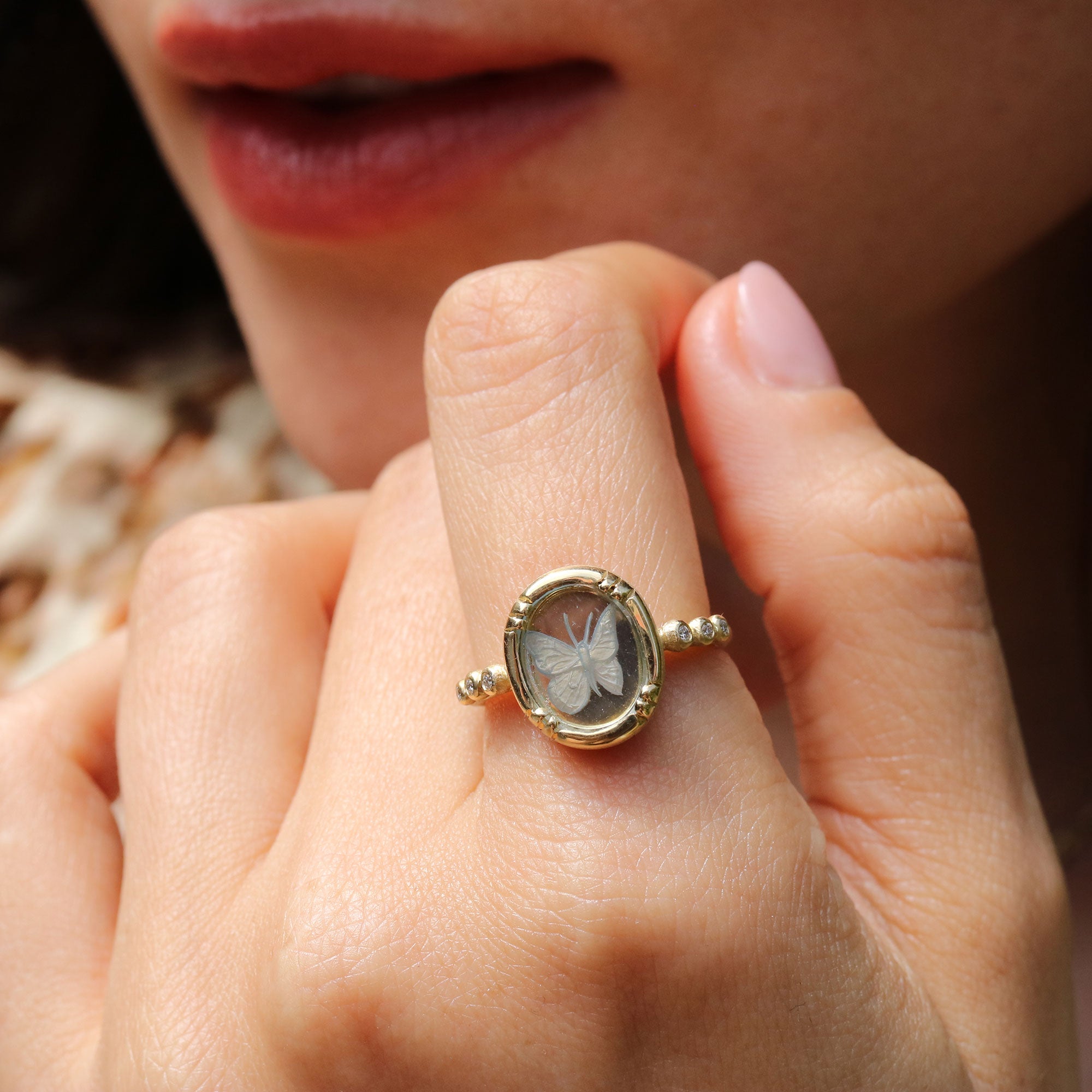 Close-up of a hand wearing a gold ring with a blue topaz butterfly design.