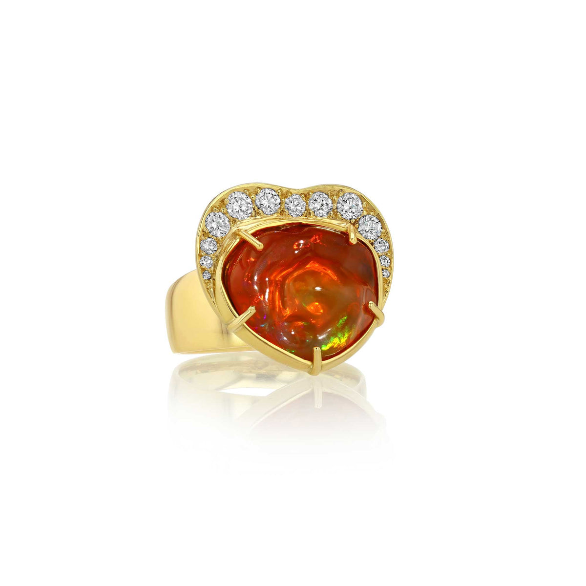 A heart-shaped gold ring featuring a large fiery orange-red cabochon fire opal gemstone in the center, surrounded by a halo of small diamond stones, shown on a white background with a soft reflection.