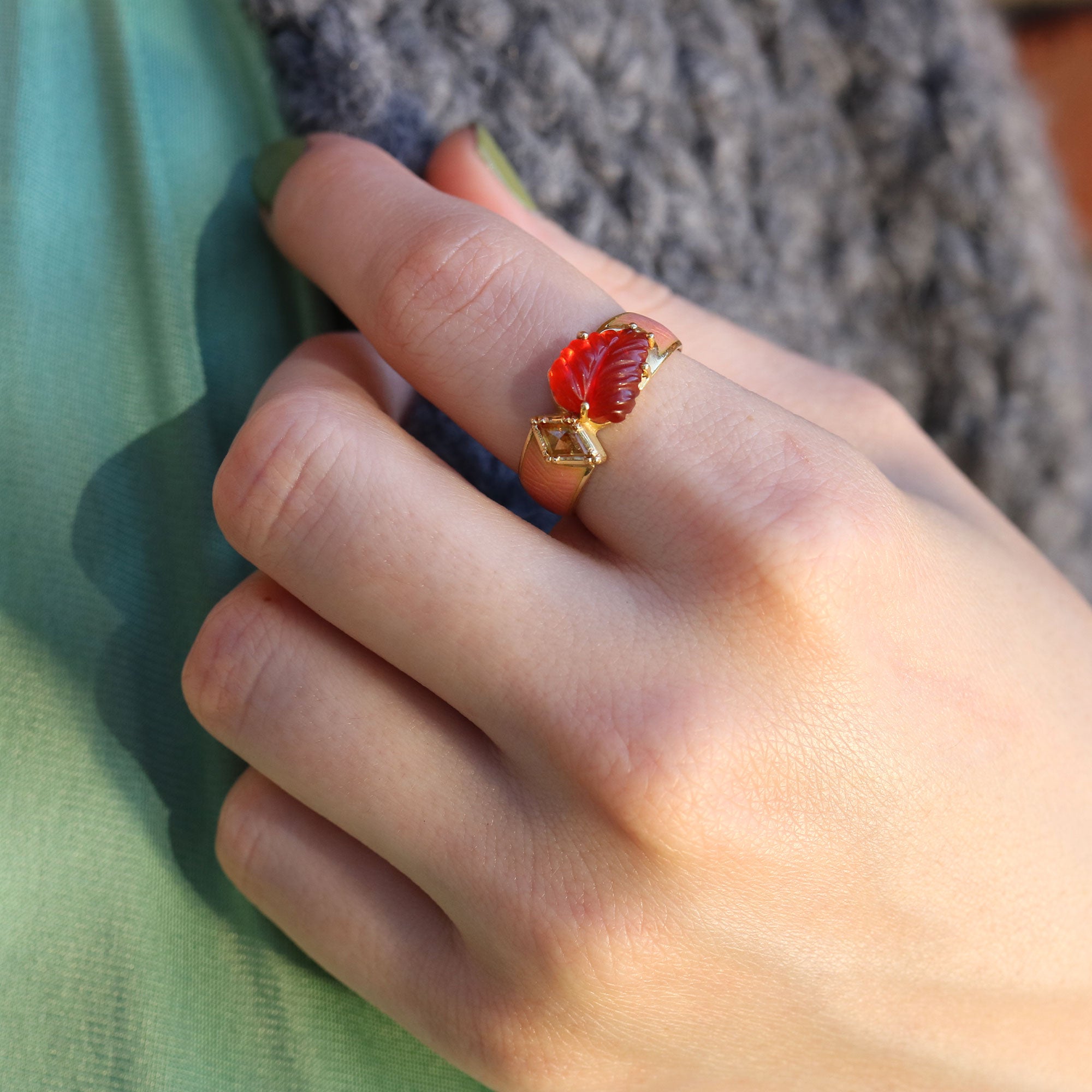 hand wearing a pink enamel with red fire opal stone ring