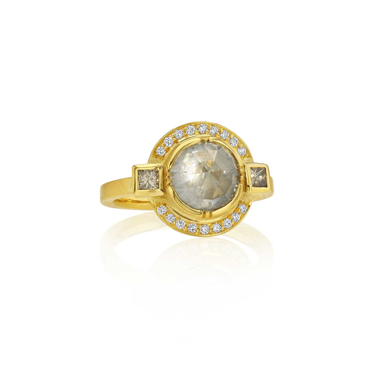 An 18k yellow gold ring featuring a central raw diamond rosecut gemstone flanked by two princess cut diamond stones, and white diamond pave halo, set against a clean white background with a soft reflection. Designed by Brooke Gregson handmade in London studio.