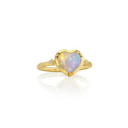 A gold ring featuring a heart-shaped opal center stone with iridescent colors, accented by small diamond stones on either side of the band, shown on a white background with a soft reflection.