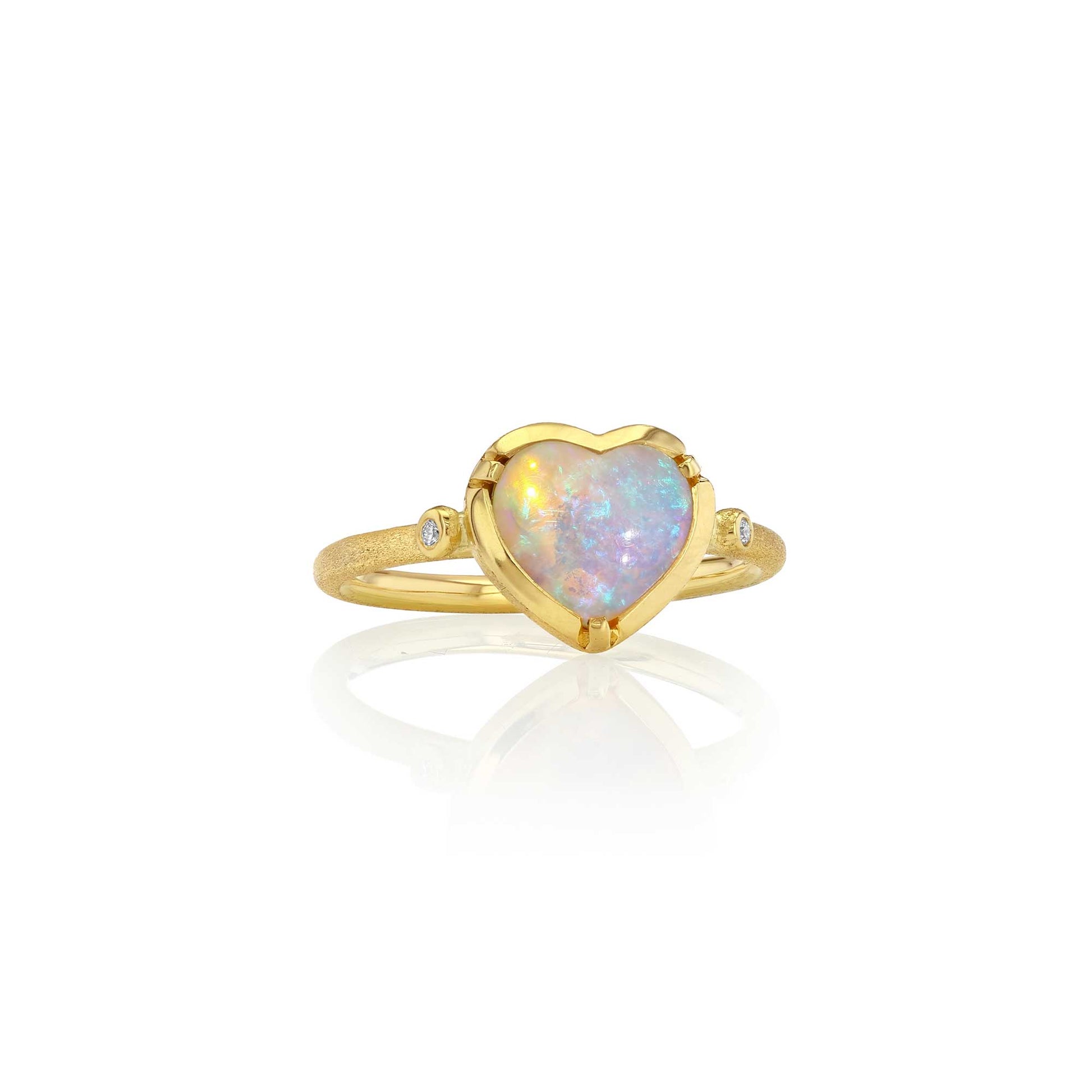 A gold ring featuring a heart-shaped opal center stone with iridescent colors, accented by small diamond stones on either side of the band, shown on a white background with a soft reflection.