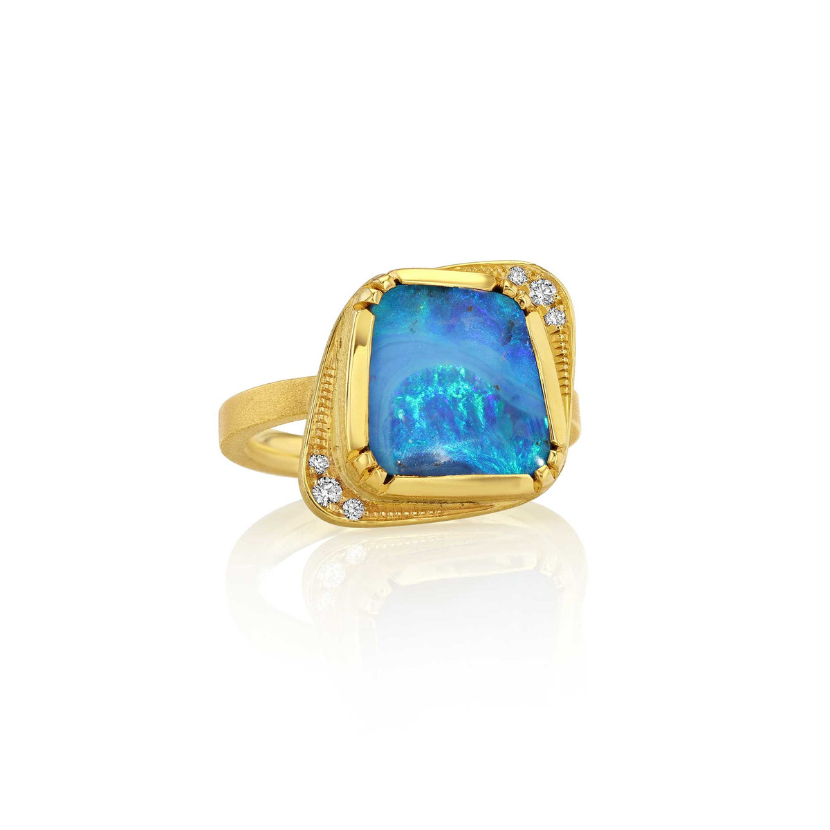 An 18k yellow gold ring featuring a large, irregularly shaped boulder opal stone with vibrant blue, purple, iridescent colors, accented by small diamond gemstones on the outsides, set against a clean white background with a soft reflection. designer by brooke gregson jewelry.