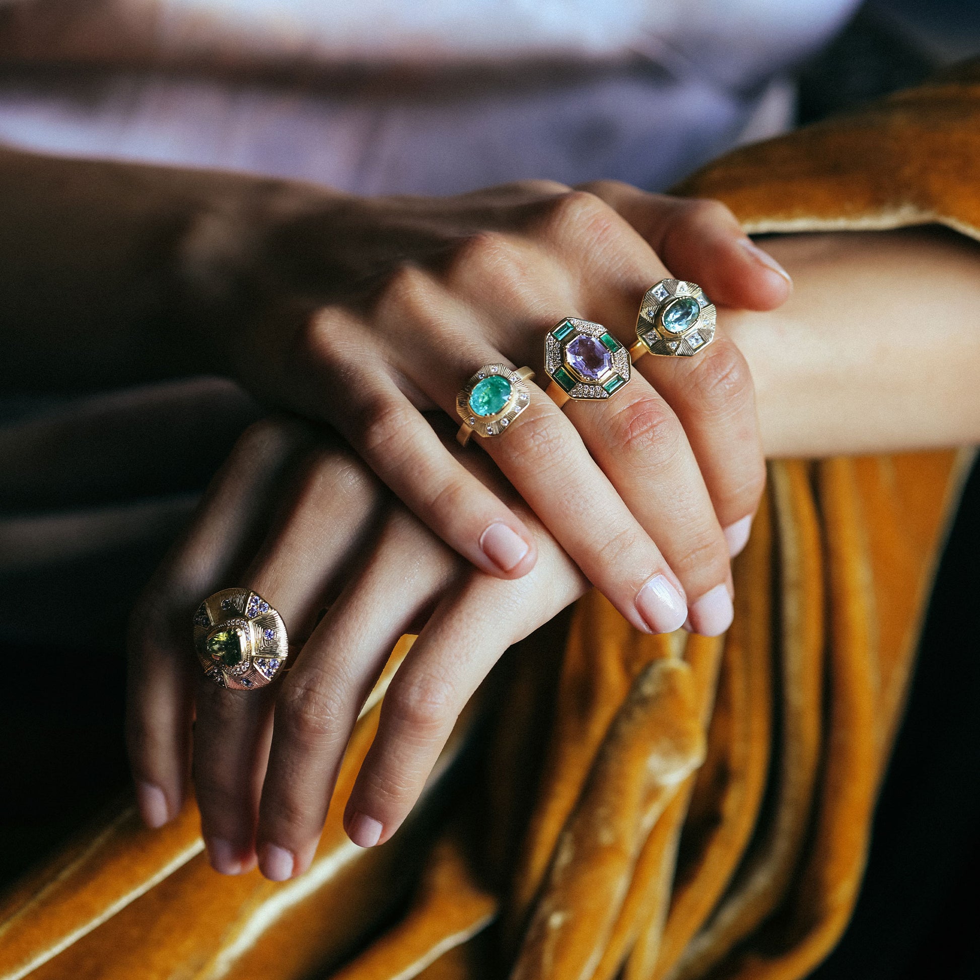 Close-up of hands wearing multiple rings with gemstones on a blurred background