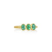 Gold ring with three green paraiba tourmaline gemstones on a white background