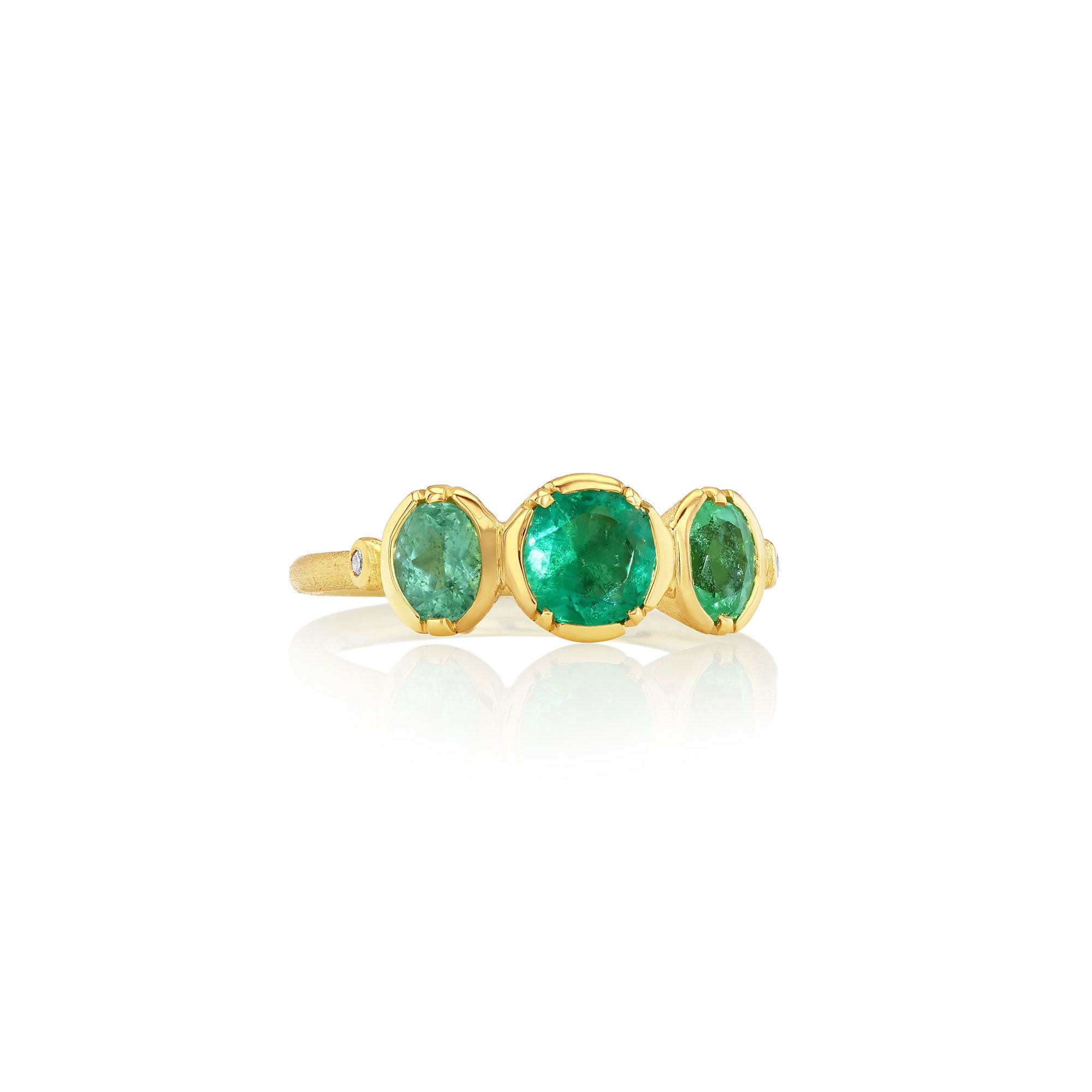 Gold ring with three green emerald and paraiba tourmaline gemstones on a white background