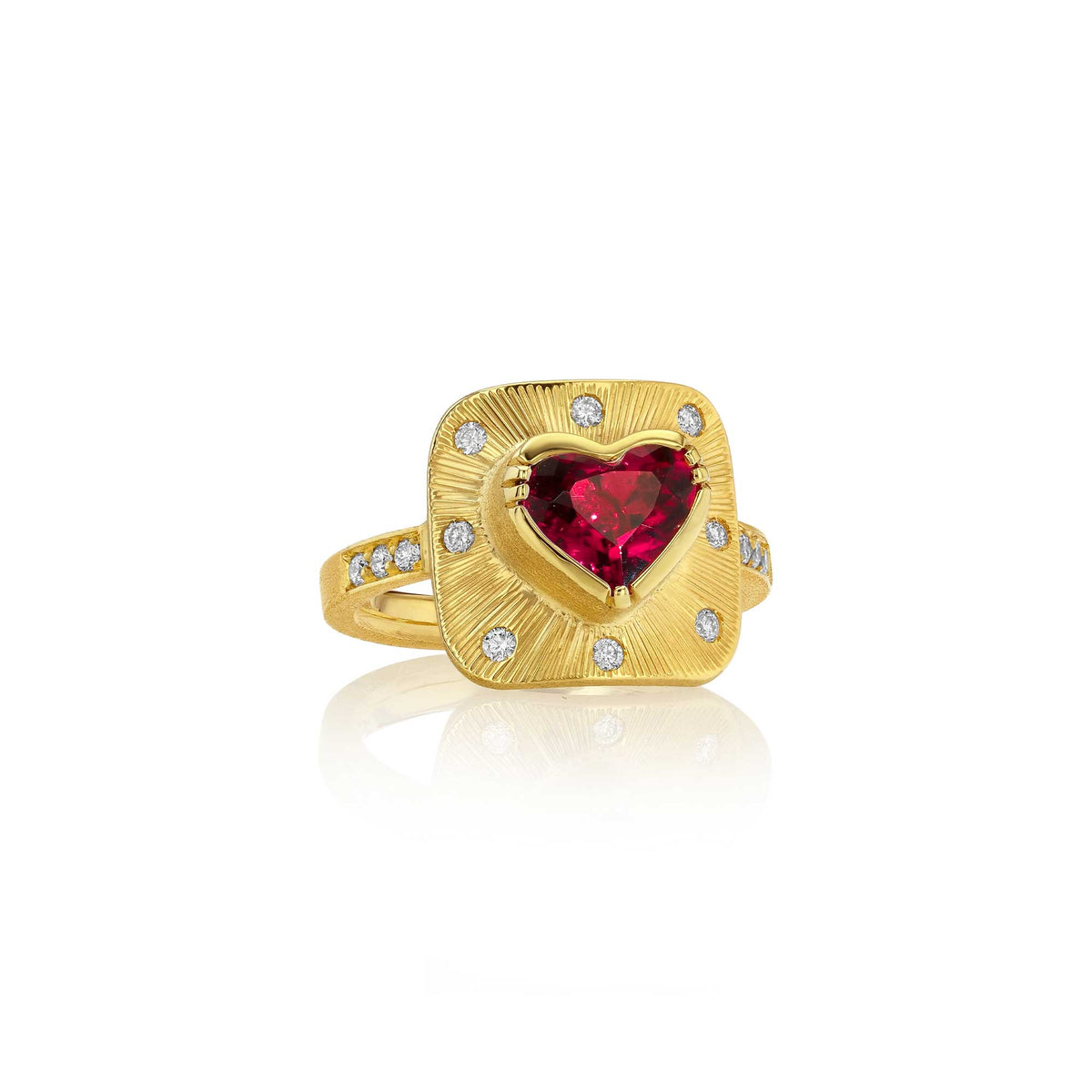 A yellow gold ring featuring a central heart-shaped red tourmaline gemstone surrounded by a square halo of small clear diamond stones, set against a clean white background with a soft reflection.