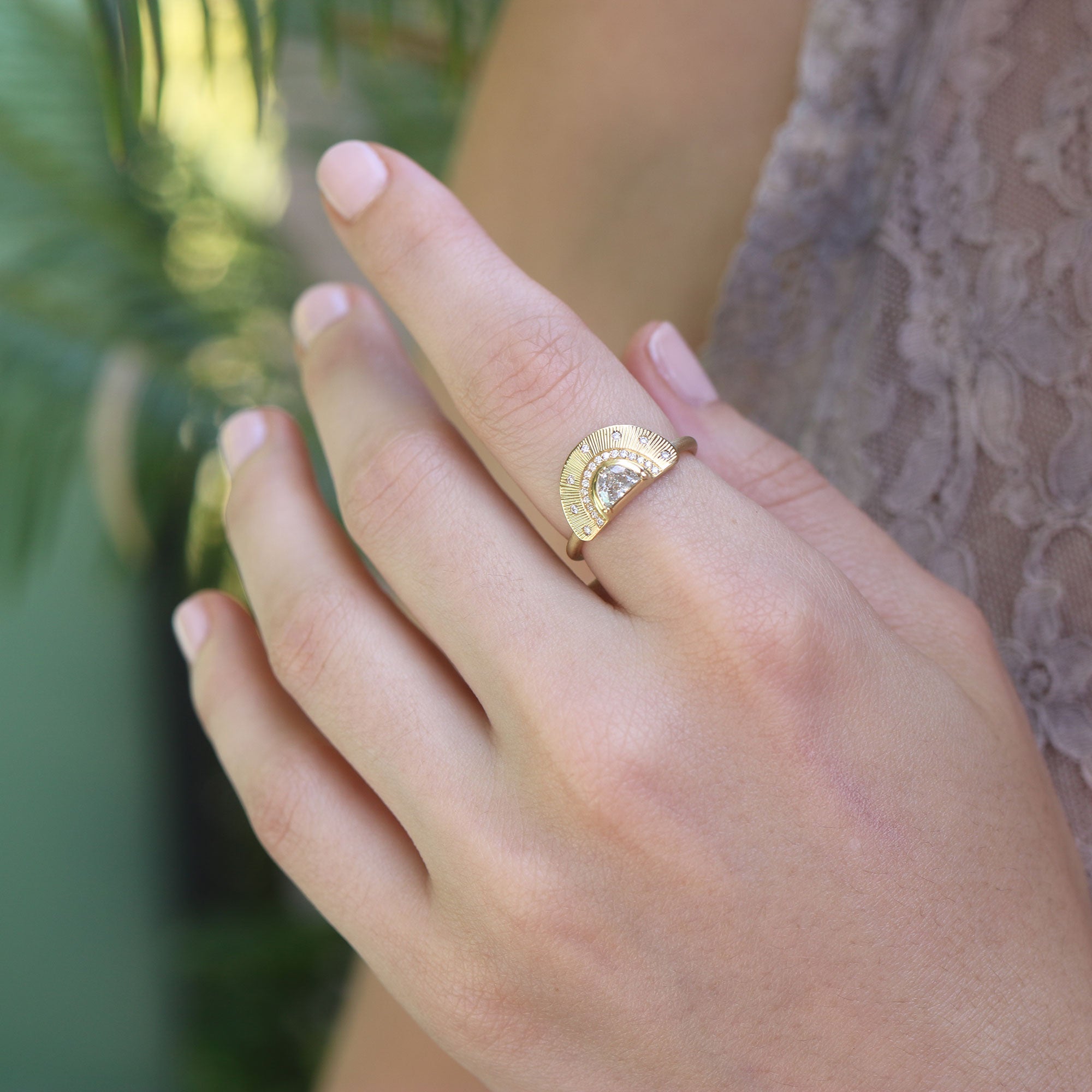 lifestyle shot of a hand wearing an 18k yellow gold hand engraved ring with white diamond stones.